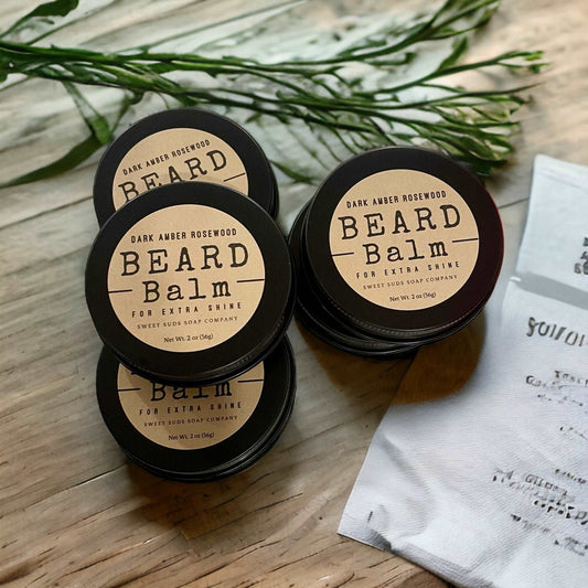 a couple of jars of beard balm sitting on top of a wooden table